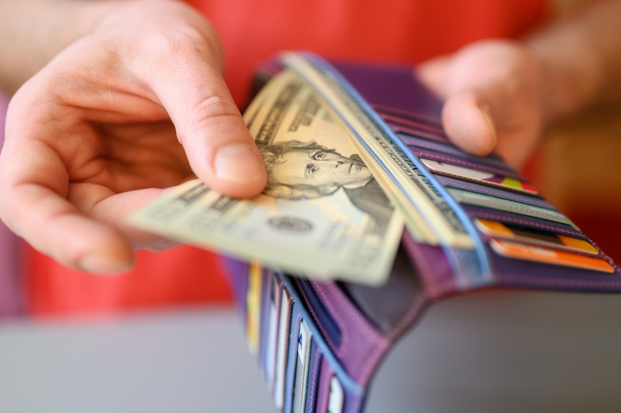 men's hands hold 20 dollar bills and a wallet on a gray table