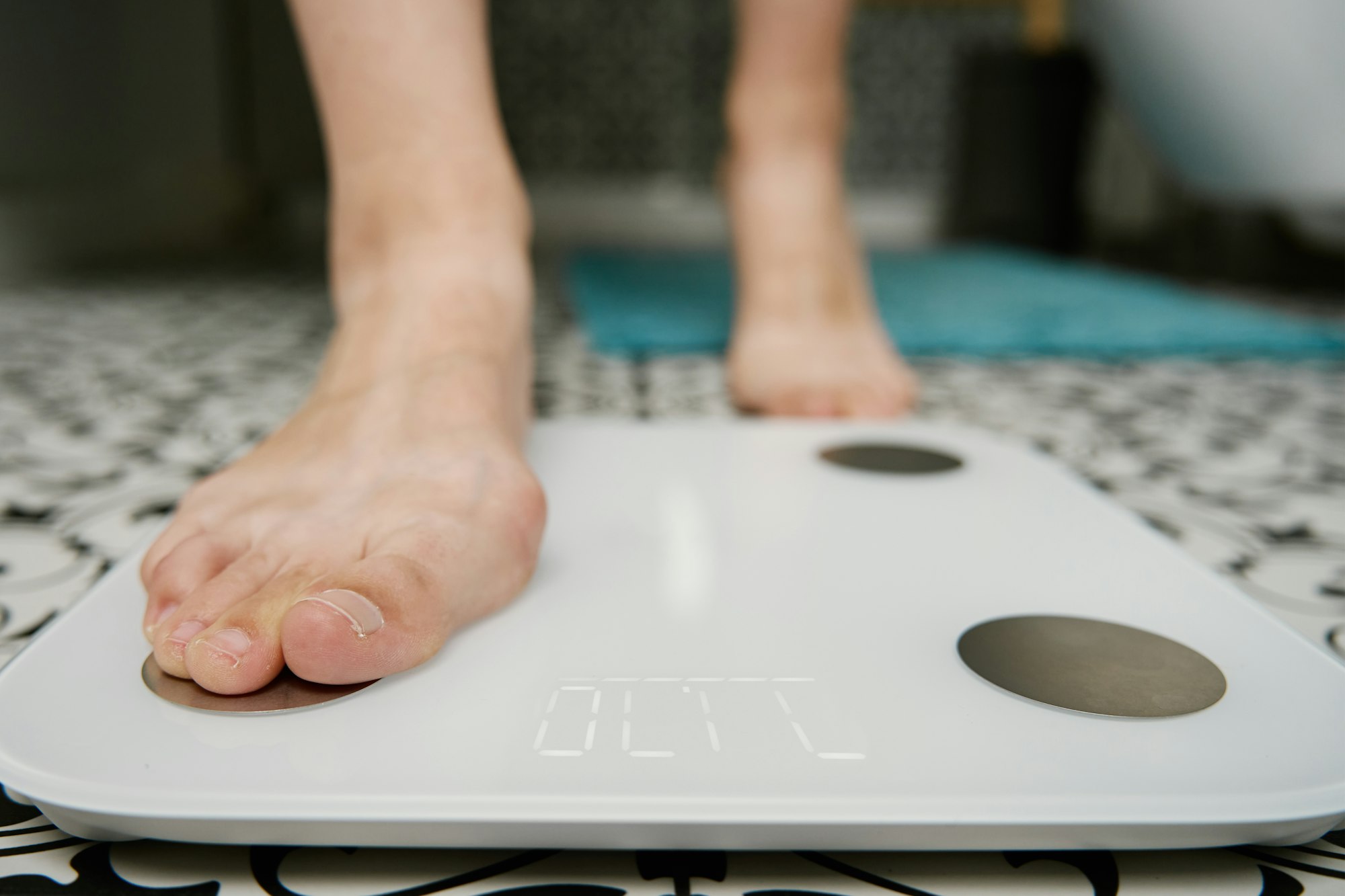 Woman checking her weight on weighing scales in bathroom